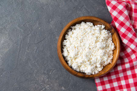 Homemade fresh cottage cheese in a round wooden bowl, healthy breakfast concept, top viewの写真素材