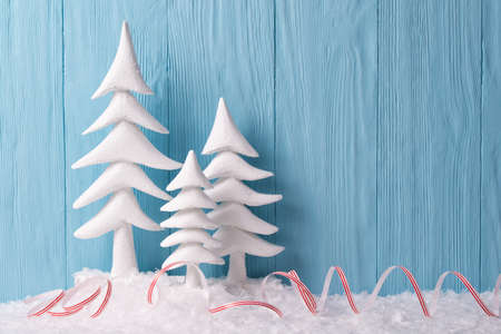 Christmas background with white christmas trees and snow, blue wooden backgroundの写真素材