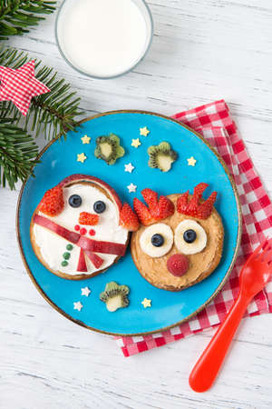 Christmas pancakes in a shape of deer and snowman made of fresh fruits and berries and glass of fresh milk. Healthy food for kids ideas. Top viewの写真素材