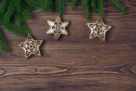 Christmas background with fir frame, golden stars and snowflakes, wooden backgroundの写真素材