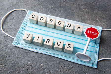 Blue disposable face mask with letters and text coronavirus and stop sign, top view, health conceptの写真素材