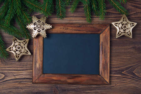 Merry Christmas decorations, empty chalkboard and frame made of fir, snowflake and stars on a timber backgroundの写真素材