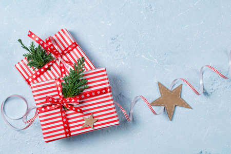 Christmas gift boxes decorated with ribbon and green branches on stone tableの写真素材