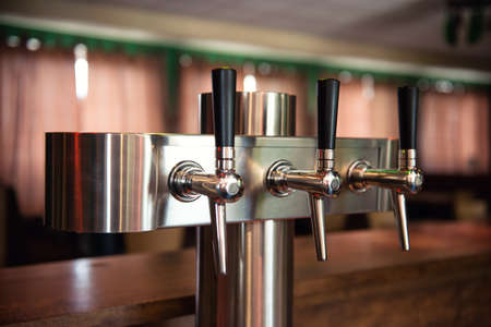 Beer tap in the bar, modern metal cider draft taps in a row
