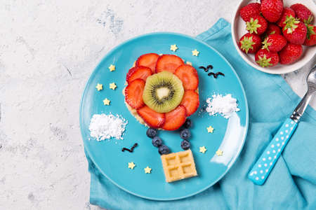 Sweet waffles with fruits in a shape of air balloon in the sky, meal for kids idea, top viewの写真素材