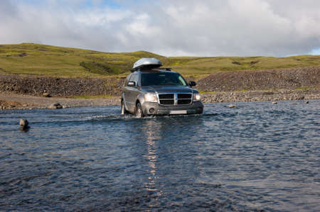LAKAGIGAR, ICELAND - AUGUST 27, 2012: Off road driving in Iceland. Dirty gray Jeep Dodge Durango with rood box crossing the river on the way to Laki Craters.のeditorial素材
