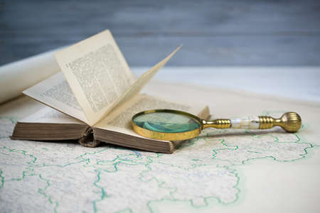 Old beautiful golden magnify glass on ancient book and old mapの写真素材