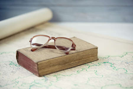 Old books and reading glasses on antique mapの写真素材