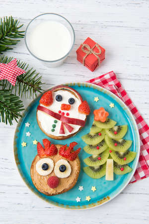 Christmas pancakes in a shape of deer and snowman made of fresh fruits and berries and kiwi christmas tree. Healthy food for kids ideas. Top viewの写真素材