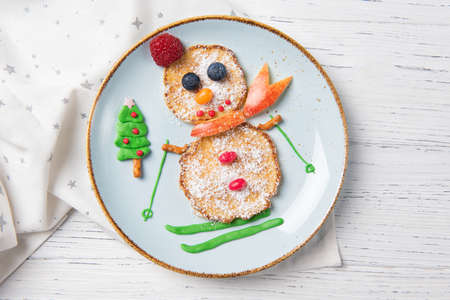 Pancakes in the shape of snowman on ski, Christmas breakfast for kids idea, top viewの写真素材
