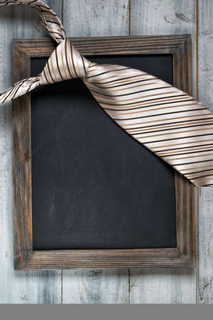 Fathers day concept, empty framed chalkboard and tie on wooden backgroundの写真素材
