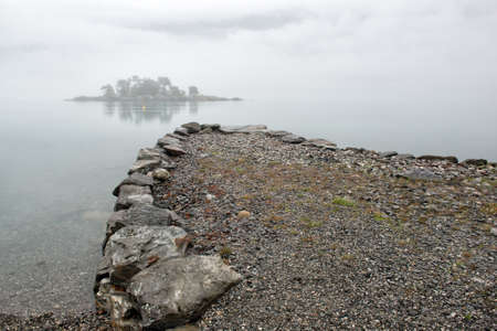 Rain and fog on the fjord, the pier and an small island in the mist, Norwayの写真素材