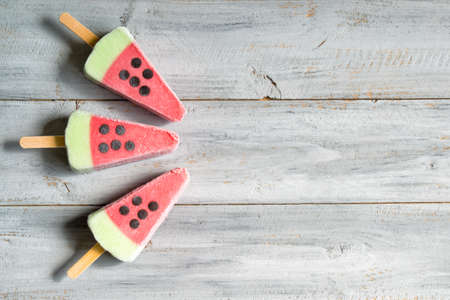 Ice cream in a shape of watermelon slices on wooden table, top viewの写真素材