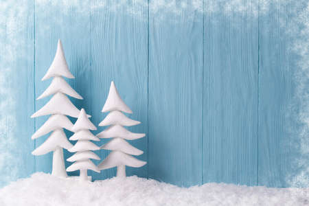 Christmas background with white christmas trees and snow, blue wooden background, snow frameの写真素材