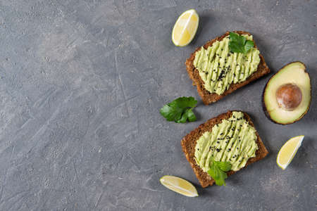 Avocado toast on whole grain bread, mashed avocado with sesame seeds and lime slices, healthy eating concept, top viewの写真素材