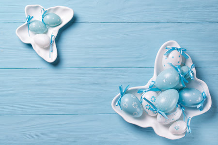 Easter eggs on butterfly shaped plates, wooden backgroundの写真素材