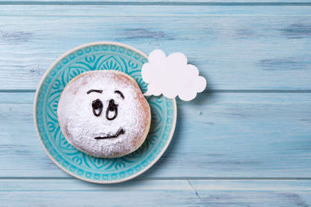 Donut with smiley face and text cloud on a plate, wooden backgroundの写真素材