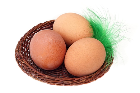three eggs in a basket and a feather isolateの写真素材