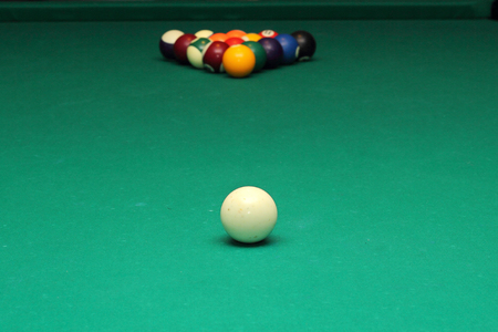 Billiard balls on green table and white ball on the foreground