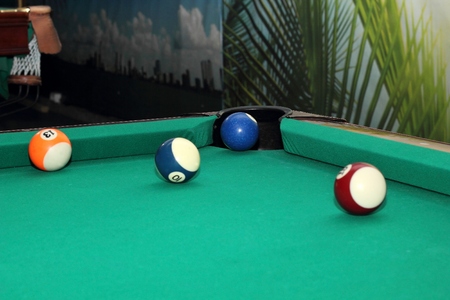 Billiard balls on green table and the blue ball in the pocket