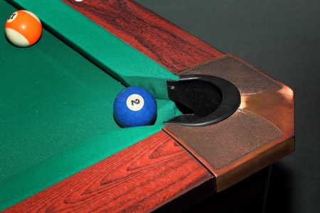 Billiard balls on green table and the blue ball in the pocket
