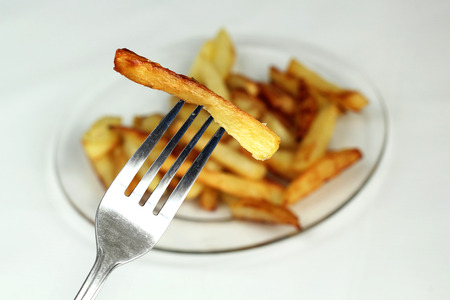 French fries on a fork in the foregroundの写真素材
