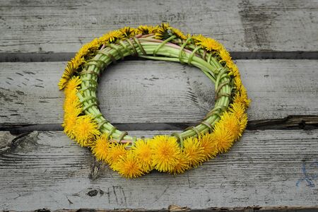 wreath of yellow dandelions on a wooden backgroundの写真素材