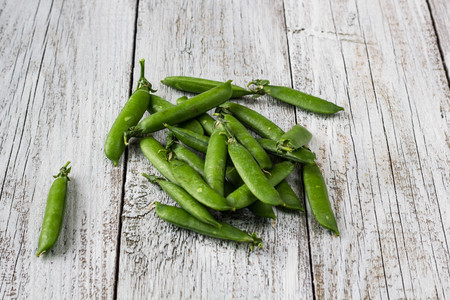 green peas pods on a white wooden table top viewの写真素材