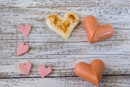 breakfast for the celebration of Valentine's day - toast in the form of hearts, sausages in a plate and a forkの写真素材