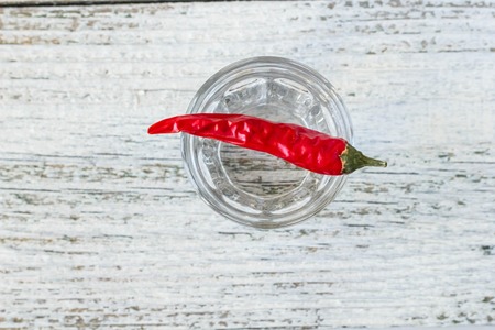 Shot of vodka with cayenne pepper on an old white wooden tableの写真素材