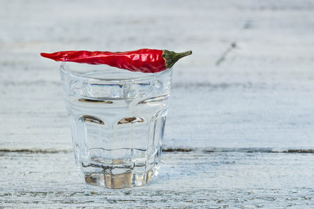 Shot of vodka with cayenne pepper on an old white wooden tableの写真素材