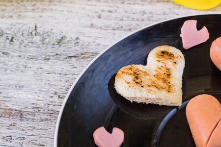 breakfast for the celebration of Valentine's day - toast in the form of hearts, sausages in a plateの写真素材