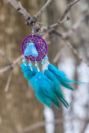Earrings of Dreamcatcher made of feathers leather beads and ropes, hanging. Handmadeの写真素材