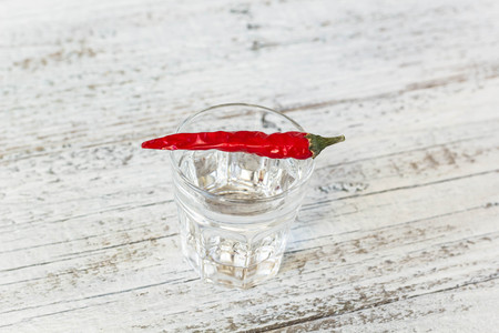 Shot of vodka with cayenne pepper on an old white wooden tableの写真素材