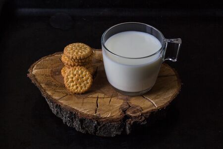 fresh healthy milk in cup and stack of cookies on black backgroundの写真素材
