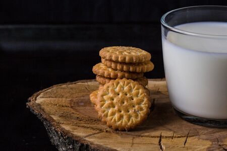 fresh healthy milk in cup and stack of cookies on black backgroundの写真素材
