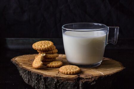 fresh healthy milk in cup and stack of cookies on black backgroundの写真素材