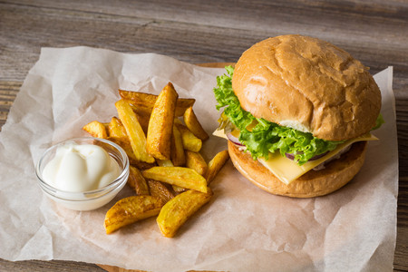Home made hamburger with chicken, onion, cucumber, lettuce and cheese on wooden rustic table with potato friesの写真素材