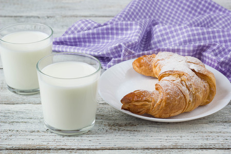 Croissant on dish with milk on old wooden table for breakfast background.の写真素材