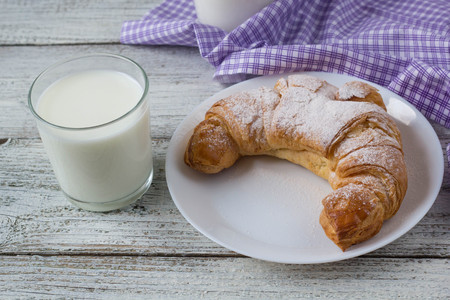 Croissant on dish with milk on old wooden table for breakfast background.の写真素材