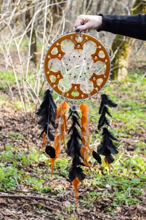 black and orange Dreamcatcher with motorcycle star made of feathers leather beads and ropes, hangingの写真素材