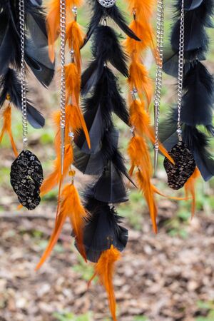 black and orange Dreamcatcher with motorcycle star made of feathers leather beads and ropes, hangingの写真素材