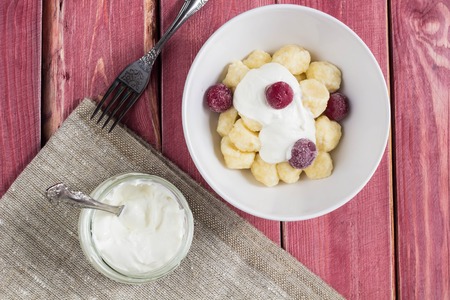 Traditional russian, ukrainian cottage cheese lazy dumplings served with sour cream and cherry on wooden backgroundの写真素材