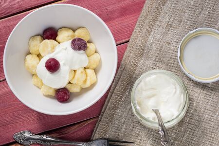 Traditional russian, ukrainian cottage cheese lazy dumplings served with sour cream and cherry on wooden backgroundの写真素材