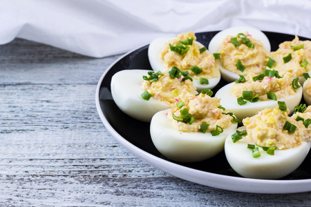 Home eggs stuffed with cheese and crab sticks topped with green onionsの写真素材