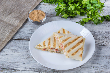 shawarma in thin pita bread with chicken and vegetables on a white plateの写真素材
