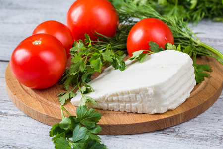 White brine cheese, knife, parsley, tomatoes on a wooden boards backgroundの写真素材