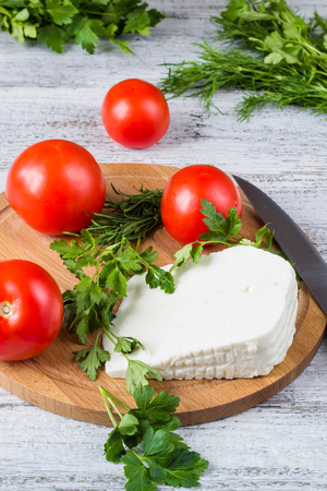 White brine cheese, knife, parsley, tomatoes on a wooden boards backgroundの写真素材