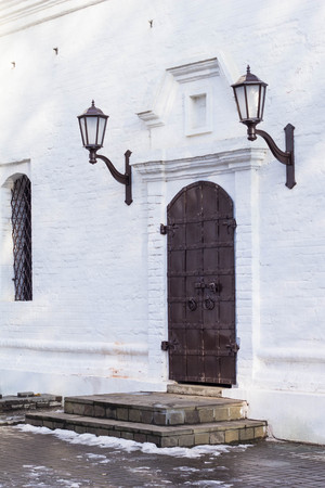 Medieval black door with metal decoration in white wall of churchの写真素材