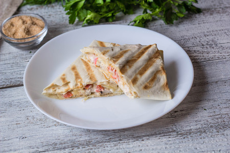 shawarma in thin pita bread with chicken and vegetables on a white plateの写真素材
